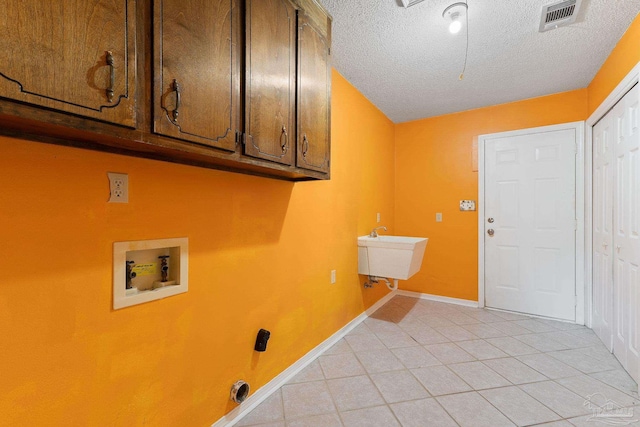 clothes washing area featuring visible vents, light tile patterned flooring, cabinet space, washer hookup, and a textured ceiling