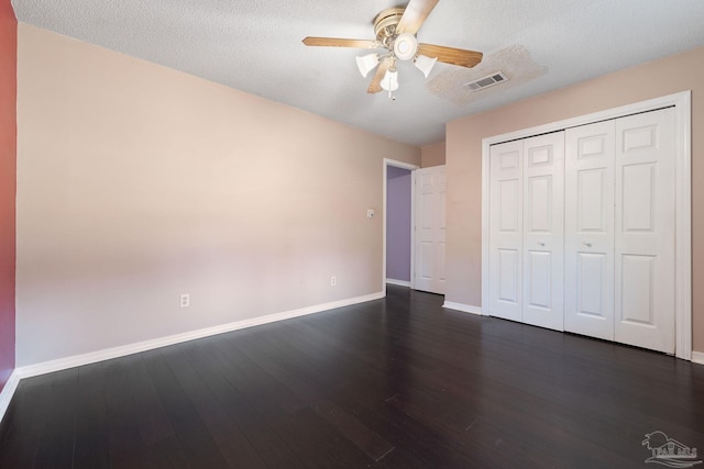 unfurnished bedroom with dark wood-style floors, visible vents, a textured ceiling, and baseboards