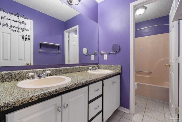 bathroom featuring tile patterned flooring, double vanity, a textured ceiling, and a sink