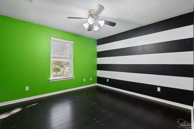 unfurnished room with an accent wall, baseboards, and wood-type flooring