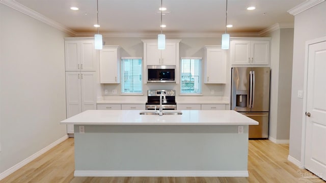 kitchen with stainless steel appliances, sink, white cabinets, hanging light fixtures, and an island with sink