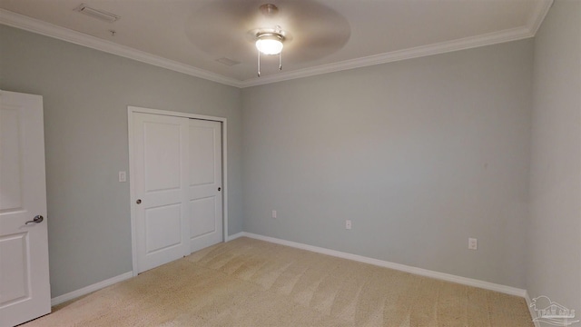 unfurnished bedroom with carpet flooring, ceiling fan, crown molding, and a closet