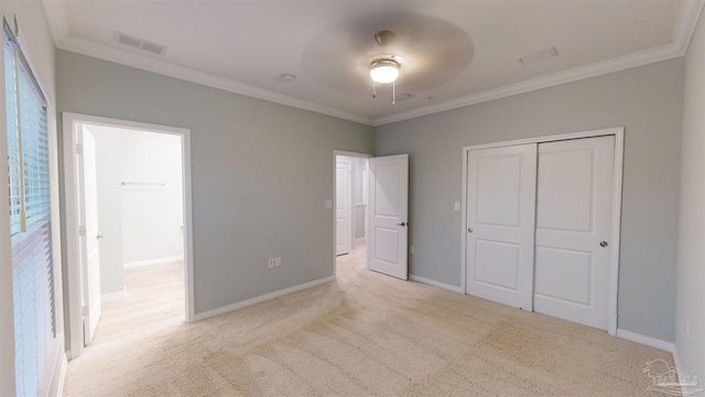 unfurnished bedroom with crown molding, ceiling fan, a closet, and light carpet