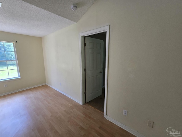 unfurnished room with baseboards, a textured ceiling, and wood finished floors