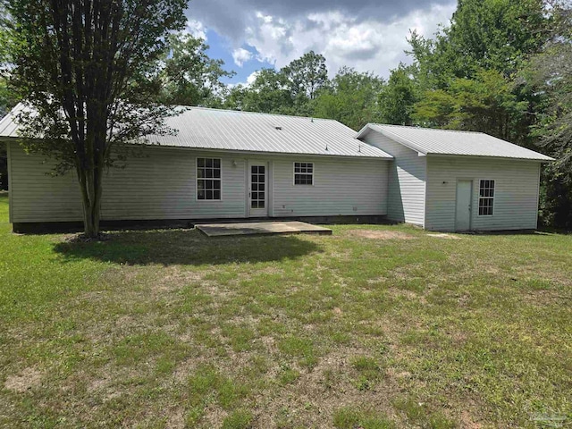 back of house featuring a patio, a yard, and metal roof