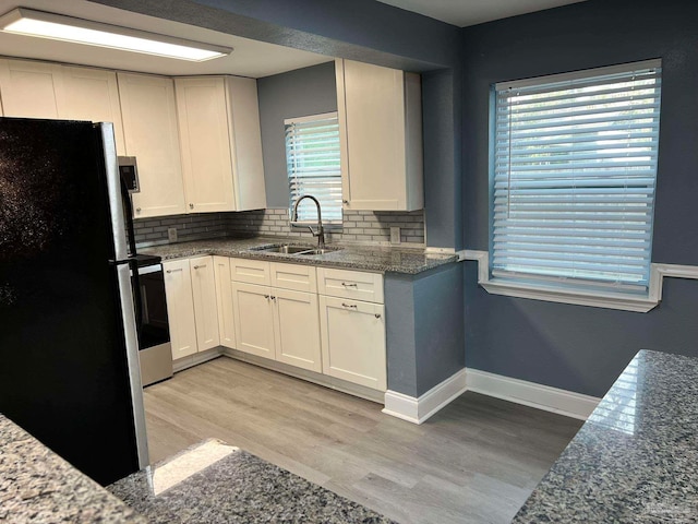 kitchen with light hardwood / wood-style flooring, black fridge, sink, and white cabinets