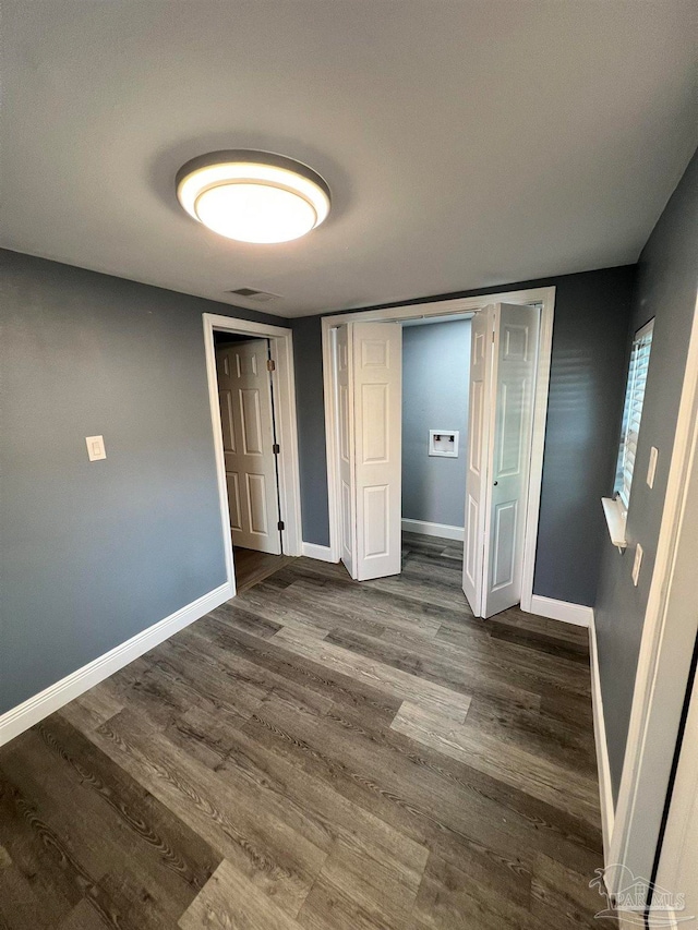 unfurnished bedroom featuring dark hardwood / wood-style flooring and a closet