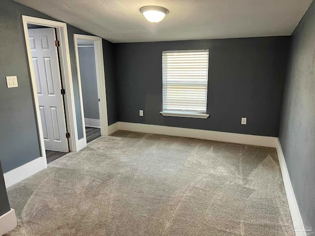 spare room with vaulted ceiling, carpet flooring, and a textured ceiling