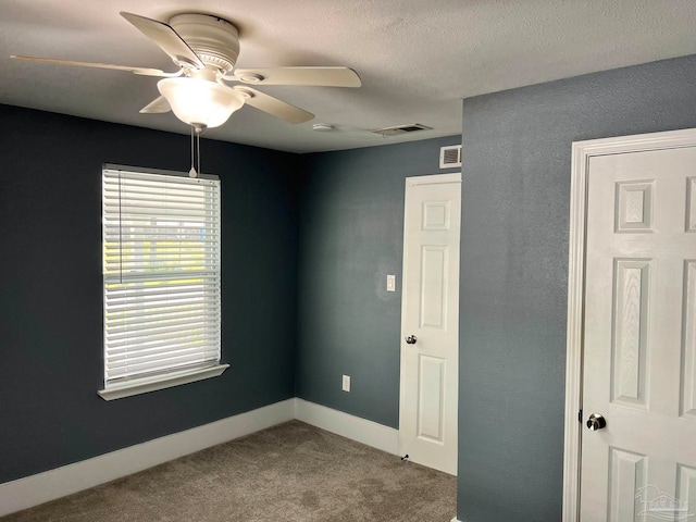 carpeted spare room featuring a textured ceiling and ceiling fan