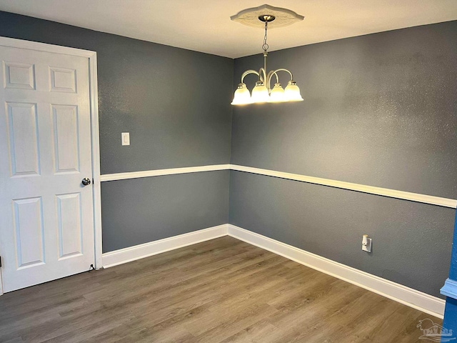 unfurnished dining area featuring an inviting chandelier and wood-type flooring