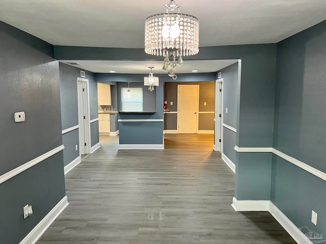 unfurnished dining area with a notable chandelier and dark hardwood / wood-style floors