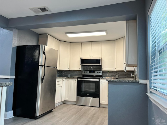 kitchen with a healthy amount of sunlight, white cabinetry, appliances with stainless steel finishes, and tasteful backsplash