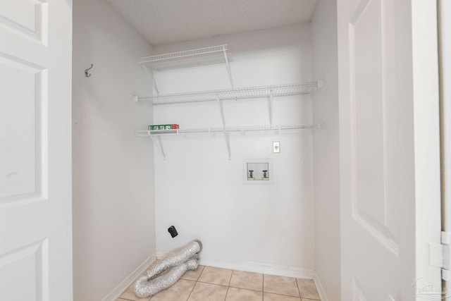 laundry area featuring light tile patterned floors, a textured ceiling, laundry area, washer hookup, and baseboards