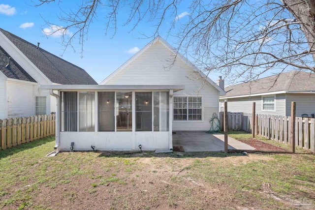 back of property with a lawn, a patio area, a fenced backyard, and a sunroom