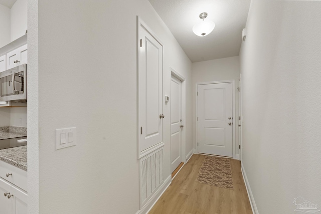 hallway with baseboards and light wood finished floors