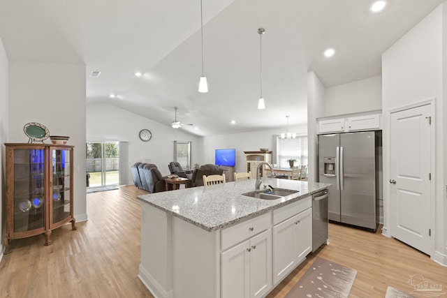 kitchen with a sink, white cabinetry, open floor plan, appliances with stainless steel finishes, and light wood-type flooring