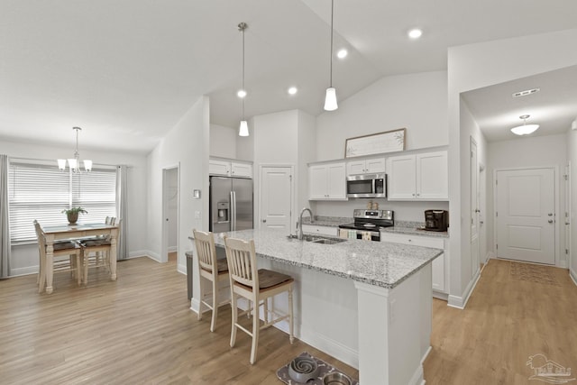 kitchen with white cabinets, light wood-style floors, stainless steel appliances, and a sink