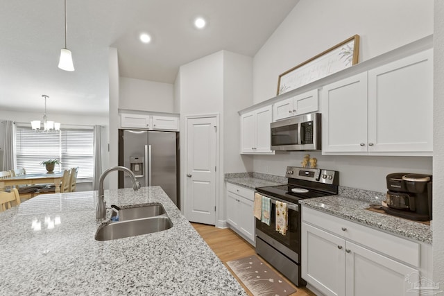 kitchen with stainless steel appliances, light wood-type flooring, white cabinetry, pendant lighting, and a sink