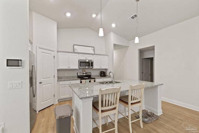 kitchen featuring a breakfast bar area, light wood-style flooring, stainless steel appliances, a sink, and white cabinetry