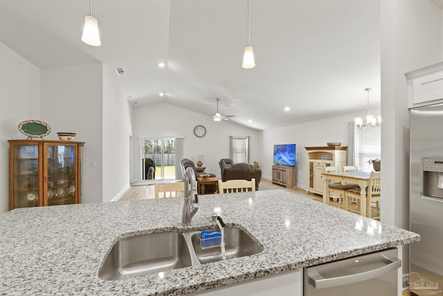 kitchen with lofted ceiling, appliances with stainless steel finishes, open floor plan, hanging light fixtures, and a sink