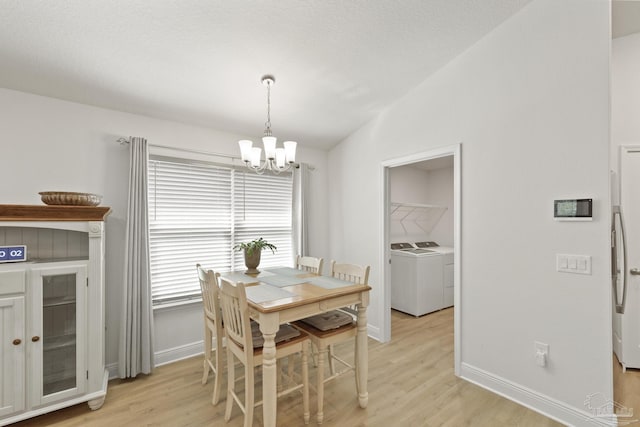 dining area with lofted ceiling, light wood finished floors, a notable chandelier, and washing machine and clothes dryer