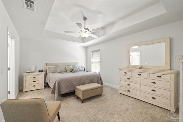 bedroom featuring a tray ceiling, light colored carpet, and visible vents