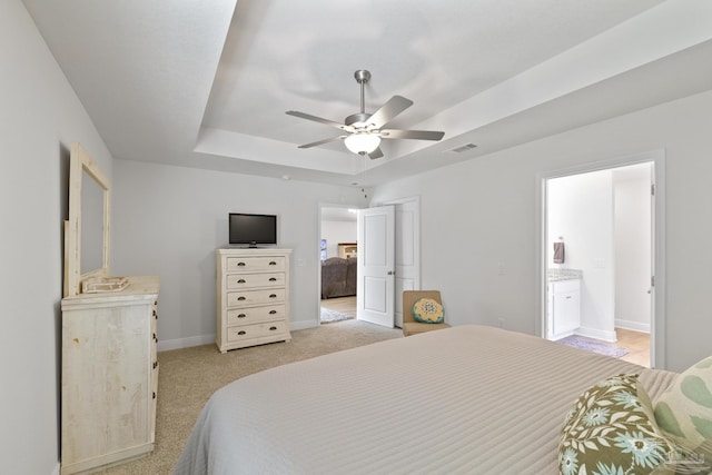 bedroom with light carpet, visible vents, baseboards, ceiling fan, and a tray ceiling