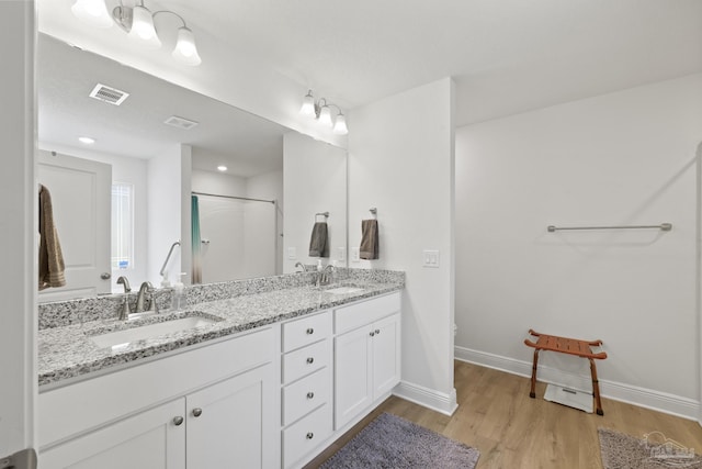 bathroom with wood finished floors, a sink, visible vents, and baseboards