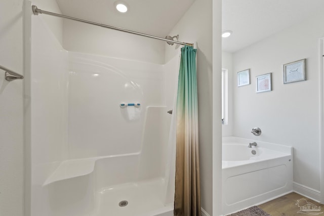 bathroom with a garden tub, a shower stall, baseboards, and recessed lighting