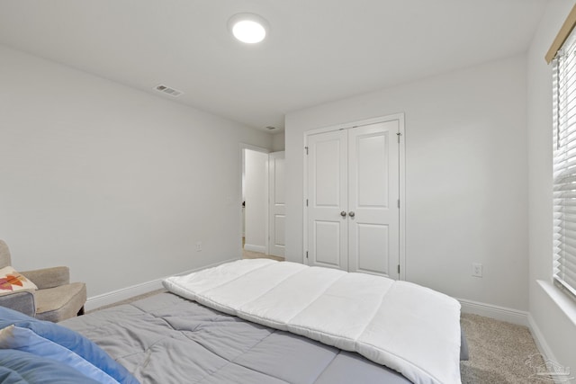 bedroom with a closet, carpet flooring, visible vents, and baseboards