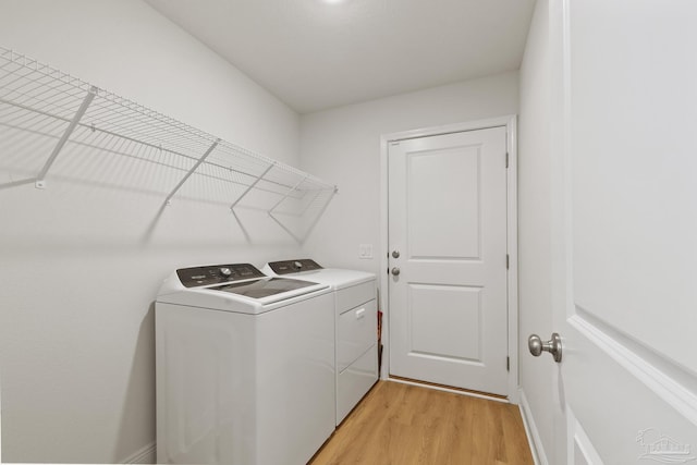 clothes washing area with laundry area, light wood-type flooring, and washing machine and clothes dryer