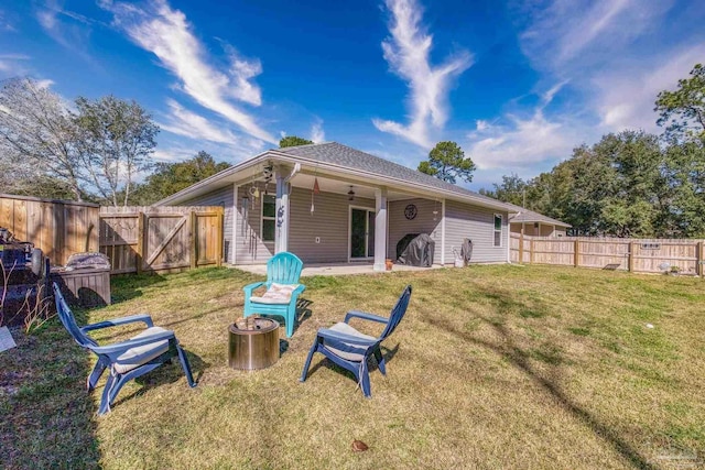 rear view of property with a fire pit, a yard, a patio, and a fenced backyard