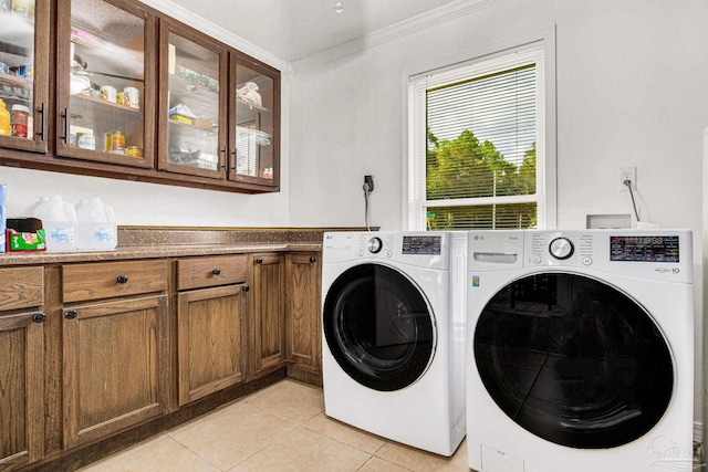 clothes washing area with washer and dryer, cabinet space, ornamental molding, and light tile patterned floors