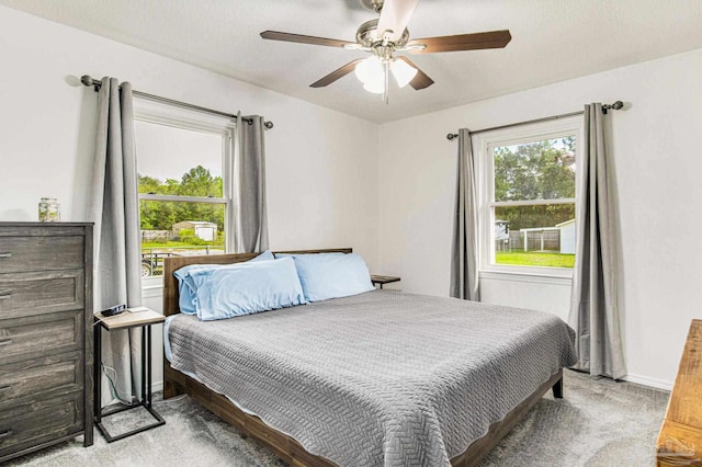 carpeted bedroom with baseboards, multiple windows, and a ceiling fan