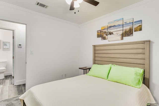 bedroom featuring visible vents, crown molding, and wood finished floors