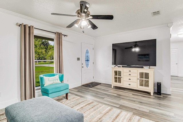 interior space with visible vents, wood finished floors, ornamental molding, and a ceiling fan