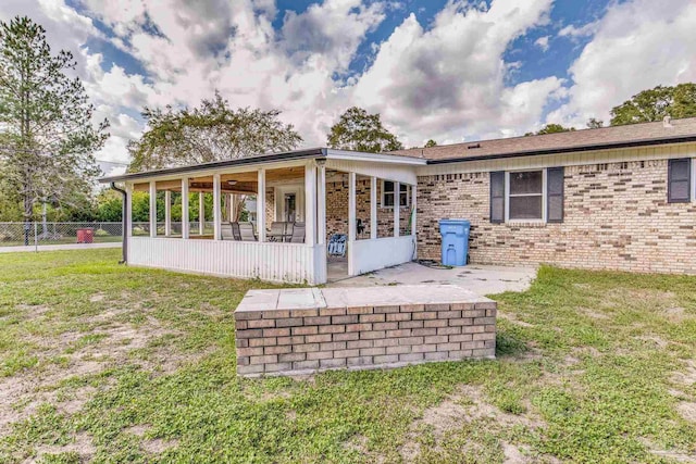 back of property with a patio, fence, a yard, a sunroom, and brick siding