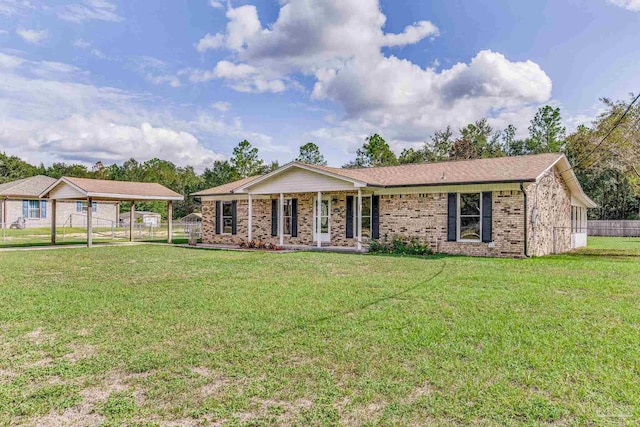 ranch-style home featuring a front lawn, fence, a detached carport, a shingled roof, and brick siding