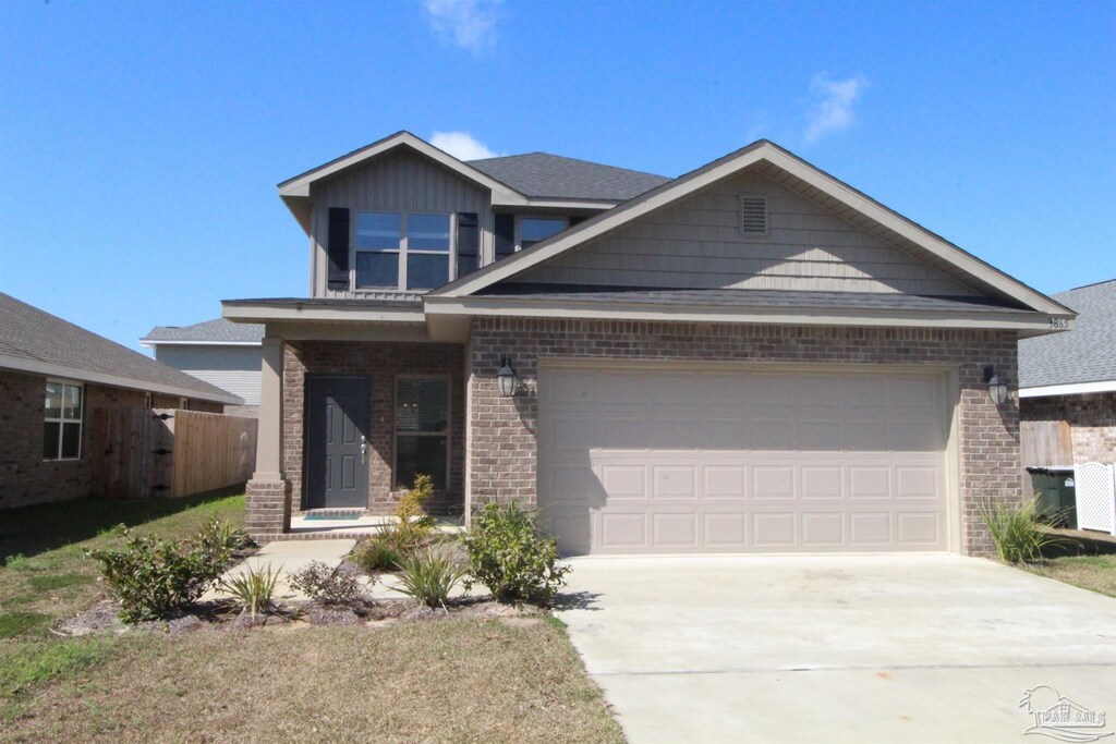 view of front of property with brick siding, driveway, an attached garage, and fence