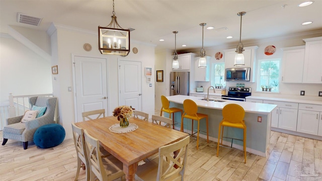 dining space with crown molding, light hardwood / wood-style floors, and sink