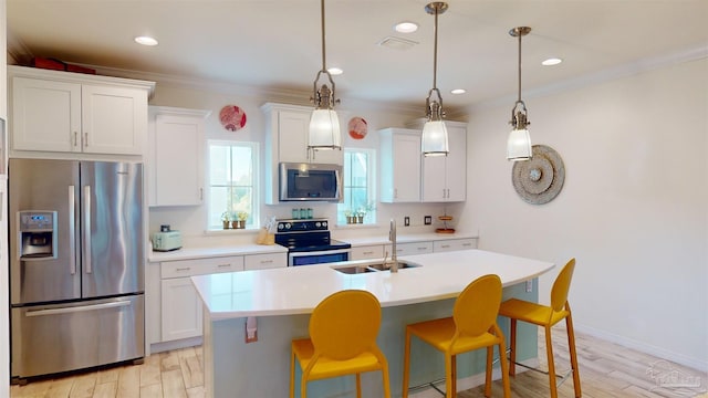 kitchen featuring sink, hanging light fixtures, an island with sink, stainless steel appliances, and white cabinets