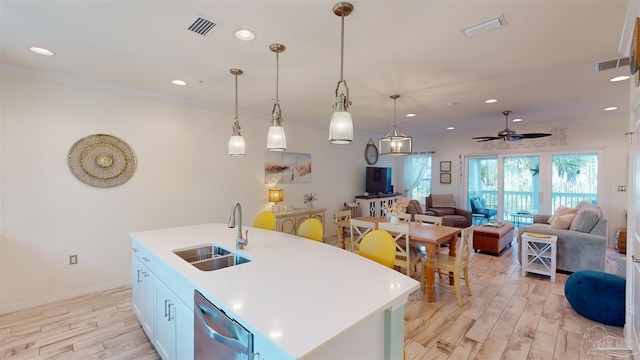 kitchen featuring sink, light hardwood / wood-style flooring, dishwasher, pendant lighting, and a kitchen island with sink