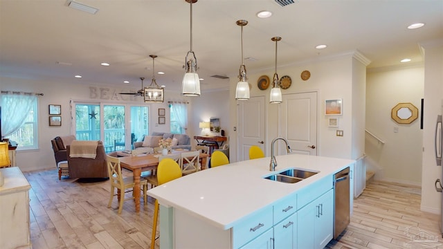 kitchen with sink, hanging light fixtures, a center island with sink, ornamental molding, and light hardwood / wood-style floors