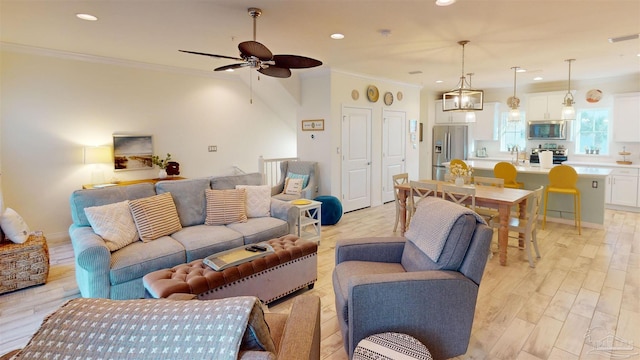 living room featuring ornamental molding, ceiling fan, and light wood-type flooring