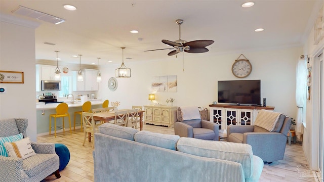 living room with crown molding, ceiling fan, sink, and light hardwood / wood-style flooring