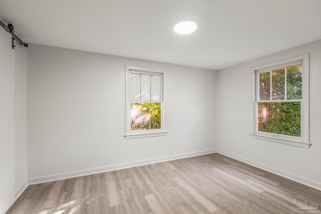 unfurnished room with light wood-type flooring and a barn door