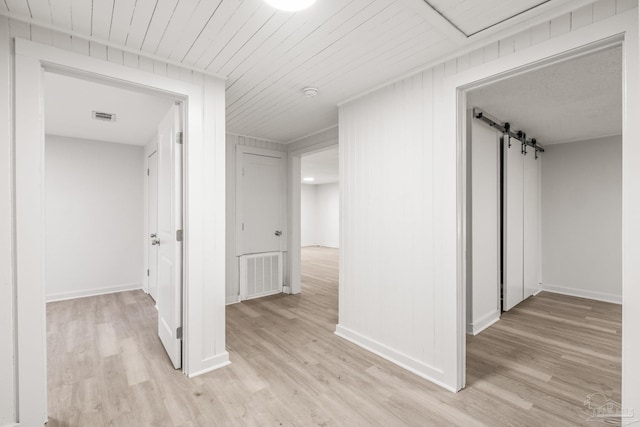 corridor featuring a barn door and light wood-type flooring