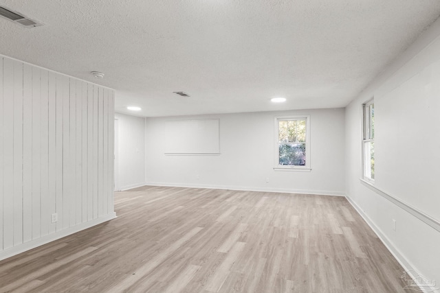 unfurnished room with a textured ceiling and light wood-type flooring