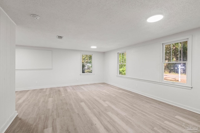 unfurnished room featuring a textured ceiling and light hardwood / wood-style flooring