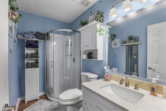 bathroom featuring visible vents, toilet, a shower stall, vanity, and wood finished floors